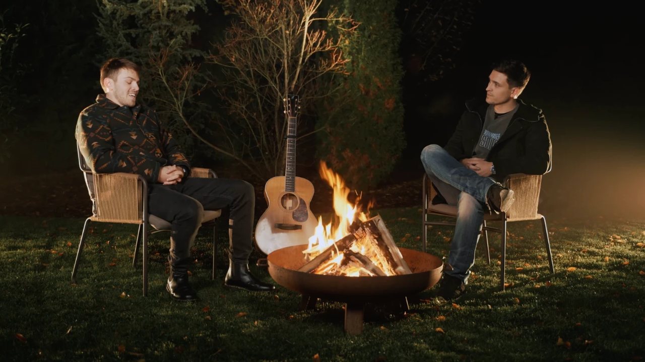 Night in a garden. Tomáš and I in two wicker chairs on either side of a fire pit, an acoustic guitar leaning against it between us.